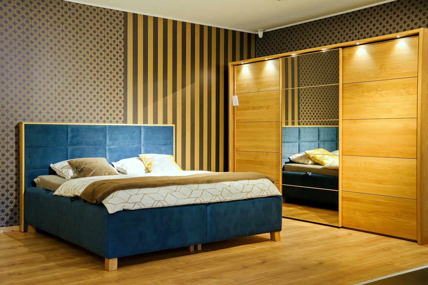 A plush blue upholstered bed and large wooden wardrobe in a bedroom.