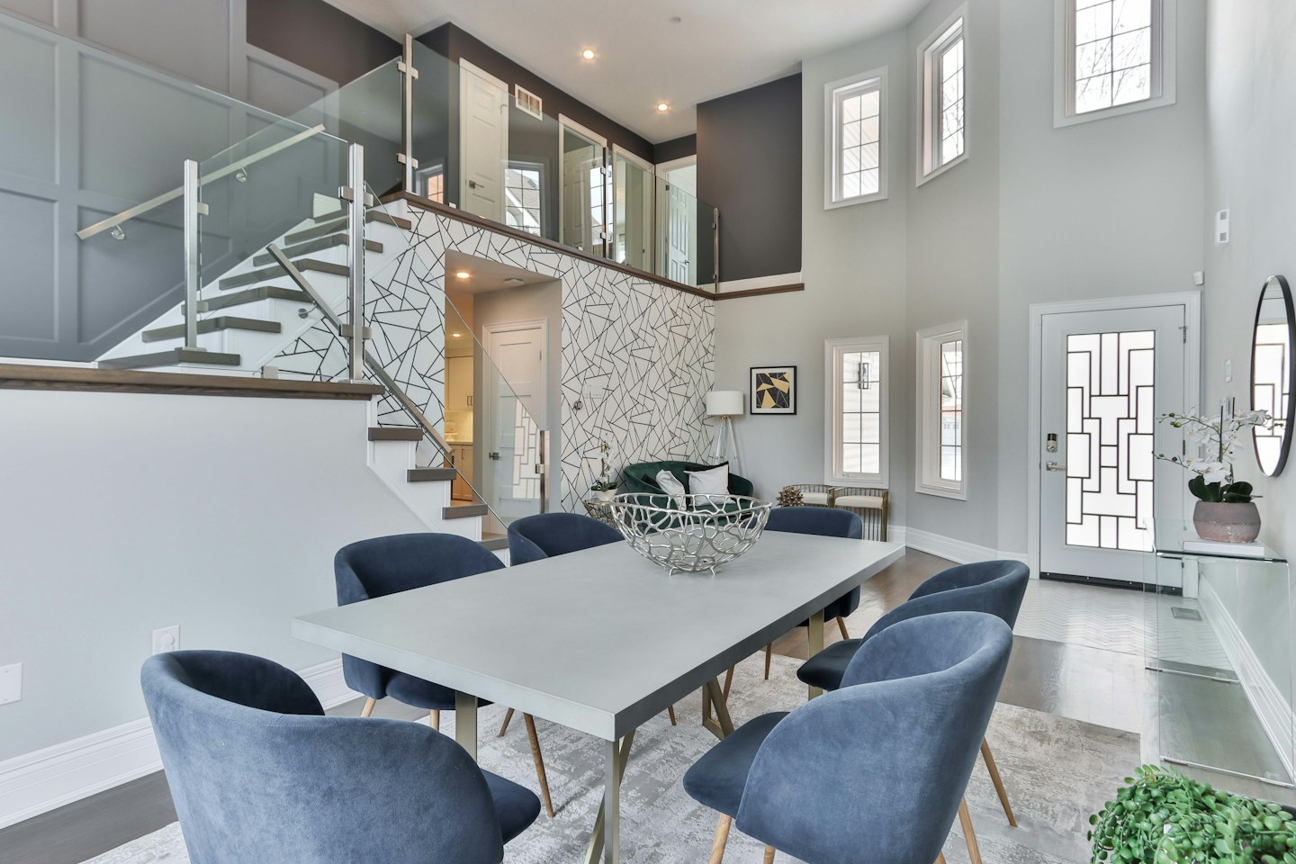 Modern dining area with blue velvet chairs and glass railing.