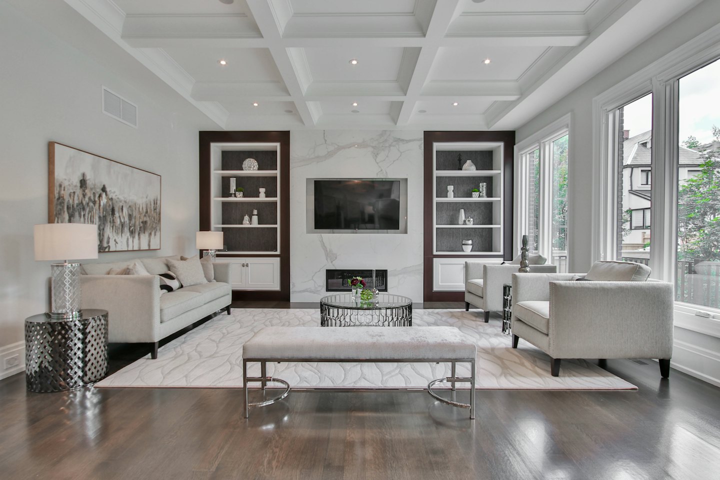 Modern living room with light furniture and TV over fireplace.